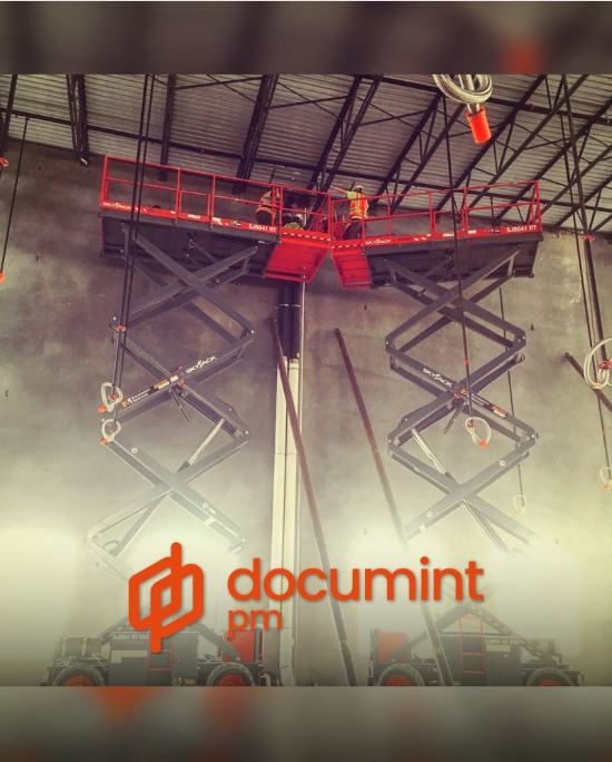 Three tradesmen on two scissor lifts hanging pipe overhead in an industrial building